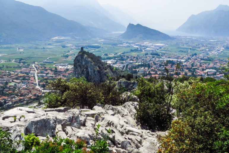 Der, gerade etwas dunstverhangene, Blick über Arco mit der Burg und den Monte Brione auf den Gardasee