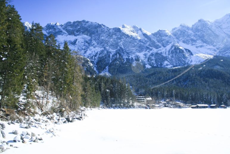 Der zugefrorene See, das Eibsee-Hotel und im Hintergrund das Wetterstein-Gebirge