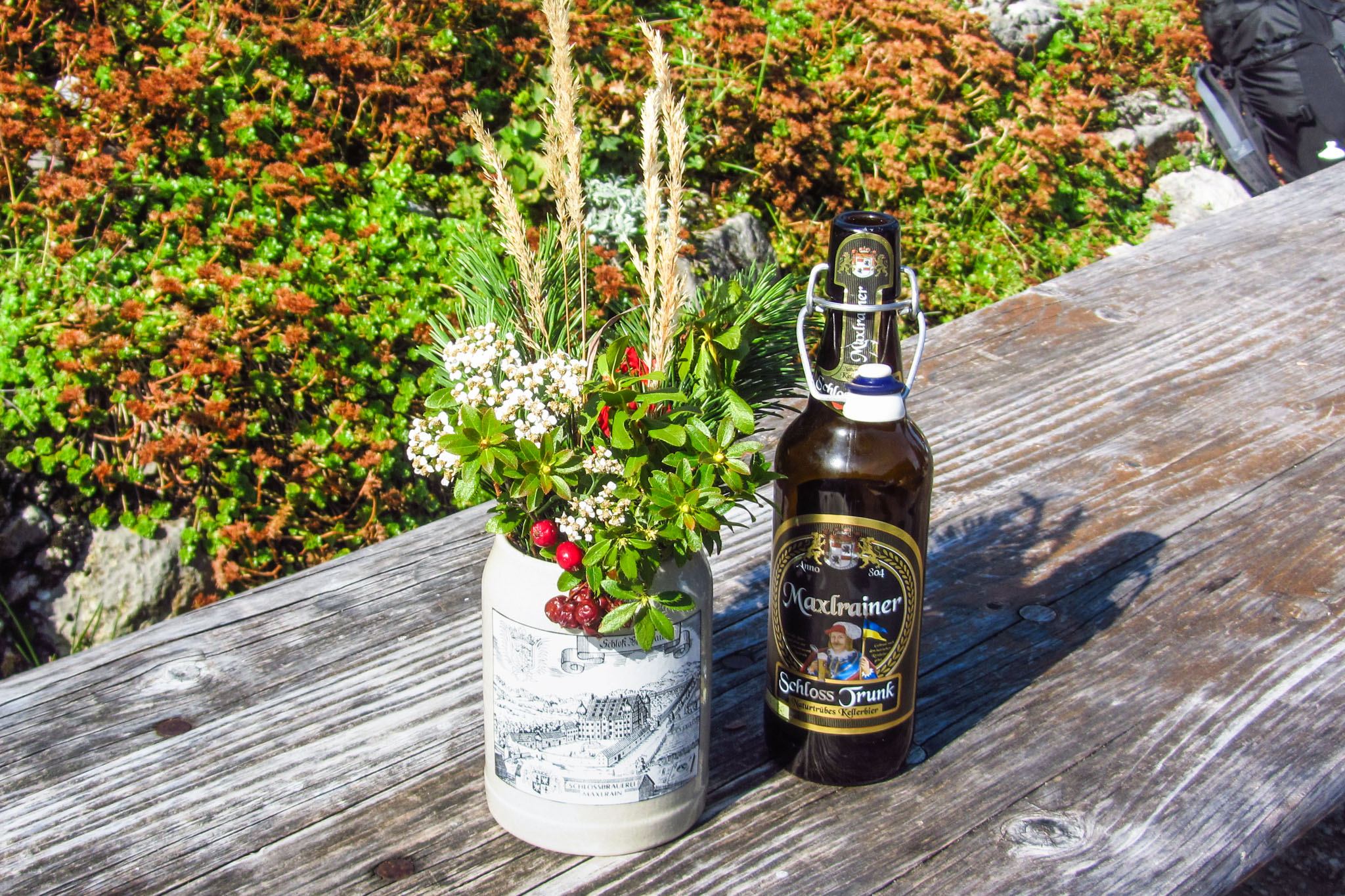 Stilleben mit Bergblumen und "Unsereiner trinkt ..."