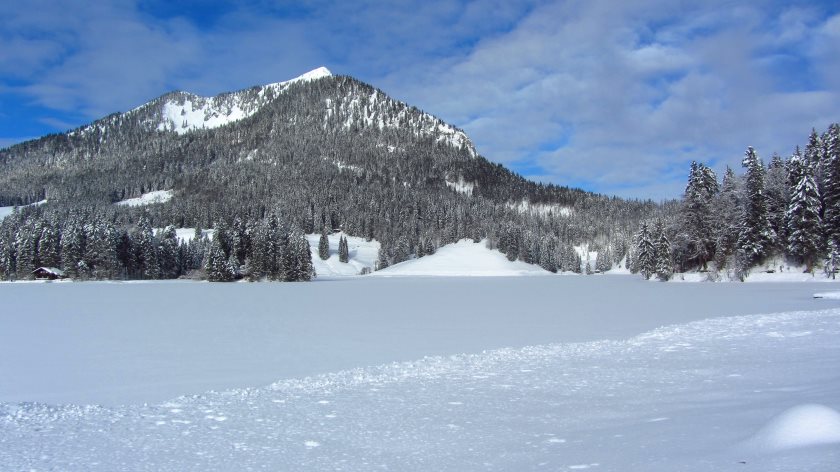 Hinter dem zugefrorenen Spitzingsee ragt der Brecherspitz auf