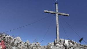 Am Spitzsteingipfel. Direkt neben dem Gipfelkreuz markiert der Grenzstein die Grenze zwischen Deutschland und Österreich. Chiemgauer Alpen