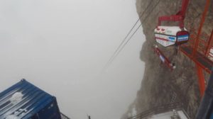 Eine Materialseilbahn der Baustelle. Die Seile verschwinden nach wenigen Metern im Nebel