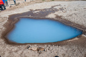 Wie klein der milchig-blaue See ist, sieht man an den Menschen am Bildrand