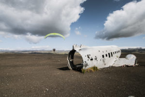 Ein motorisierter Paraglider fliegt um das Flugzeugwrack herum