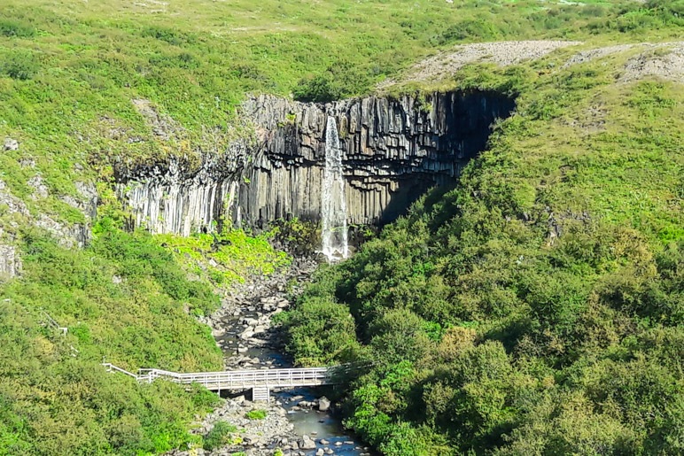 Der Svartifoss liegt inmitten einer grünen Landschaft