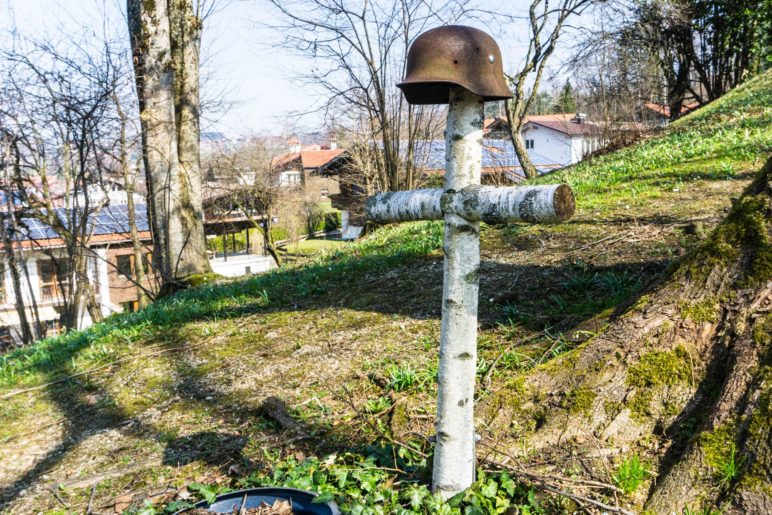 Das Kreuz aus Birkenstämmen mit dem Stahlhelm steht neben der Kriegerkapelle