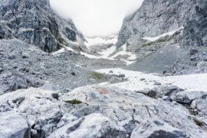 Eine ausgeblichene, rote Wegmarkierung als einziger Farbkleck in einer Welt aus Grautönen