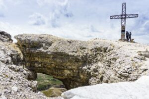 Neben dem Gipfelkreuz ist eine Felsbrücke, durch die man auf den Pass sehen kann