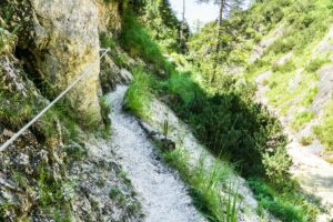 Eine Seilversicherung an einer Stelle, an der der Weg ein Stück oberhalb des Bachs verläuft