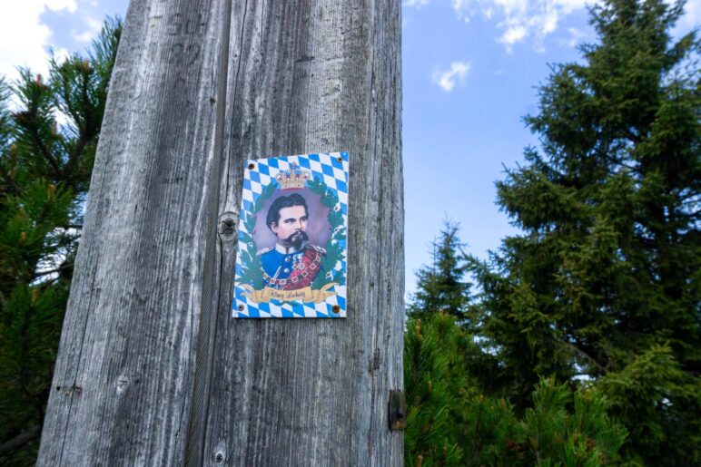 Der Kini ist auch da, als Plakette am Holzkreuz